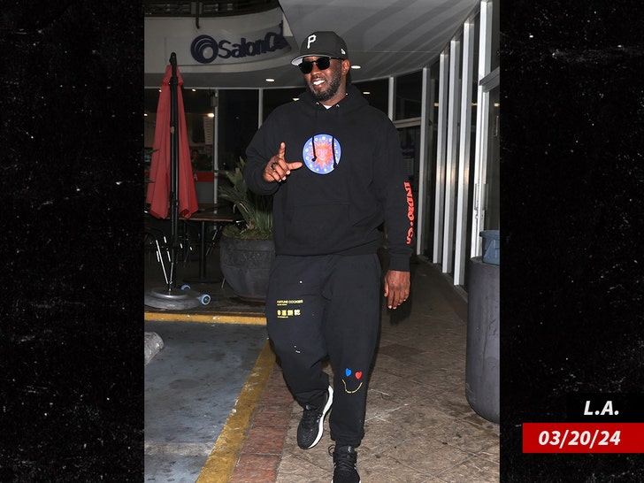 382f3048f3334872856d9f1d7a3b39cc_md Diddy walking in a shopping plaza while wearing a black sweatpants, a black hoodie, and a black hat.